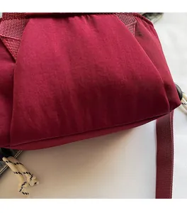 Detail of soft dark red nylon fabric with drawstring and woven shoulder strap