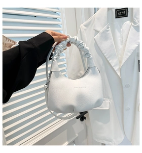 Détail d'un sac à main blanc en cuir avec anse froncée et lettrage en relief élégant