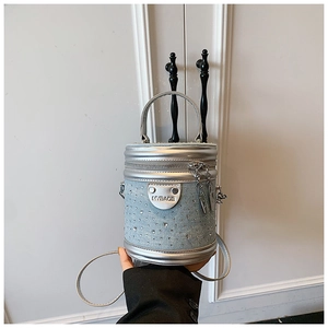 Détail du sac seau en denim bleu clair avec strass brillants et poignée argentée