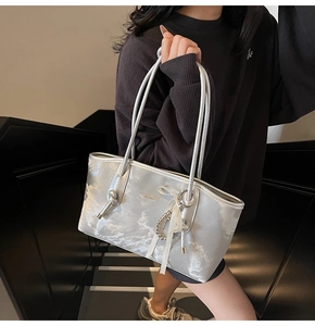 Borsa a spalla argento con fiocco bianco e ciondolo di perline tenuta da modella