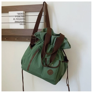 Detail view of large green canvas travel bag with brown straps and drawstring closure