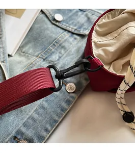 Close-up of the durable black swivel hook and red woven strap on the fabric bucket bag