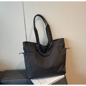 Detail of black nylon tote bag with drawstring closure and spacious dual handles