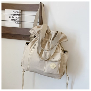Detail view of large beige canvas drawstring backpack on a wooden stand with pockets