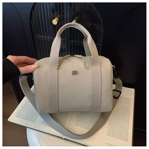 Détail macro d'un sac oreiller en nylon beige avec logo métallique et tissu texturé