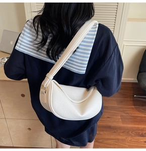 Close-up of white lychee-grain hobo bag with wide strap and golden metal hardware