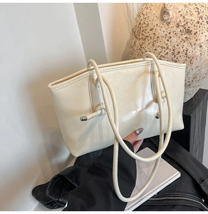 Détail du sac cabas brillant blanc cassé avec bandoulière nouée et finitions métalliques