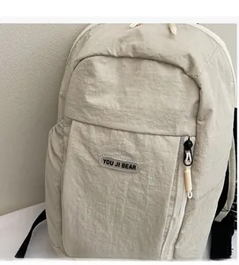 Detail of light beige casual backpack showing unique crinkled fabric and front zip pocket