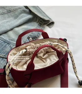 Detail view of burgundy bucket bag with an adjustable shoulder strap and drawstring closure