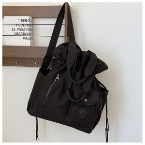 Detail of a black pleated bucket bag with functional drawstring and multiple pockets