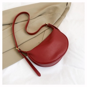 Detail der tiefroten Mondsichel-Schultertasche aus hochwertigem Leder mit Lychee-Narben
