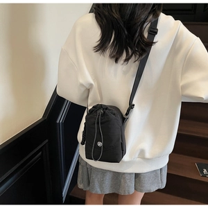 Détail du sac bandoulière en toile imperméable noire avec cordon de serrage