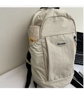 Detail of light beige nylon backpack with side pocket holding a folding umbrella