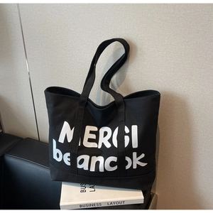 Detail shot of large capacity black canvas tote bag with white MERCI letter printing