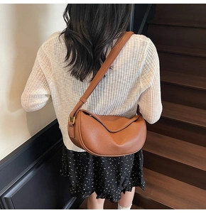 Detailed side view of caramel crescent hobo bag with pebble leather texture on a model