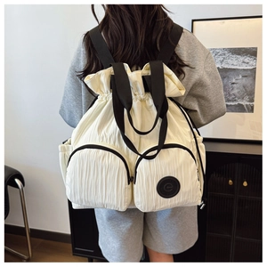 Detailed macro view of white pleated backpack with drawstring closure and two front pockets