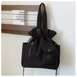 Detail view of black canvas bucket bag featuring pleated drawstring closure and utility pockets