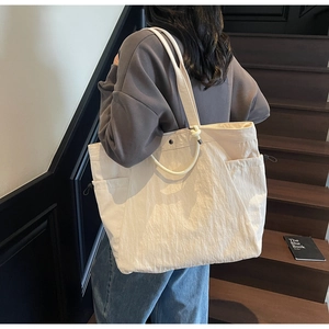 Detail of cream tote bag with wrinkled texture, round handles and side pocket
