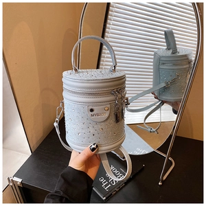 Vue détaillée du sac seau bleu clair avec strass et plaque métallique de marque