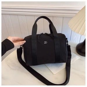 Gros plan du sac Boston noir avec logo argenté et large bandoulière en textile réglable