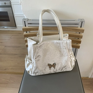 Detail of white tote bag with butterfly prints and side drawstring storage pocket
