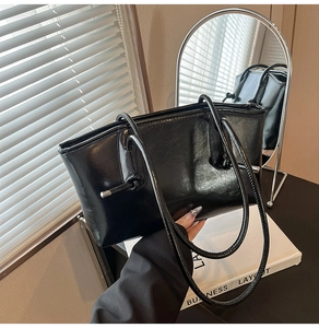 Détail d'un sac cabas en cuir verni noir avec des nœuds métalliques argentés chics