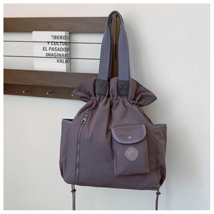 Detail of purple pleated canvas tote bag featuring drawstring closure and functional pockets