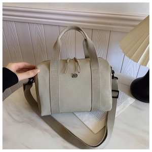 Détail du sac Boston en nylon beige sur marbre avec logo en métal mat élégant