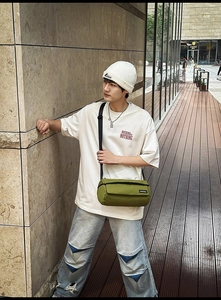 Détail du sac cylindrique en toile vert olive avec étiquette de marque et bandoulière