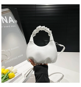 Close-up of white lychee pattern leather handbag with ruffled handle and elegant texture