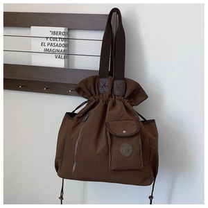 Detail of dark brown canvas tote bag featuring drawstring closure and magnetic front pocket