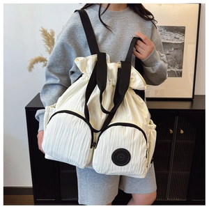 Detail of cream white pleated backpack featuring dual front pockets and drawstring closure