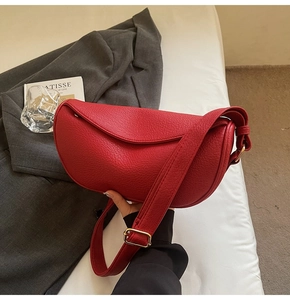 Detailed macro view of red lychee grain leather texture on half moon crossbody bag