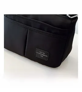Detail of black canvas crossbody bag showing front slip pockets and vintage fashion label