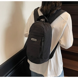 Detail shot of a black minimalist nylon backpack with vertical zipper and brand label