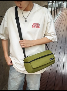 Détail du sac bandoulière cylindrique vert mousse avec sangle en nylon noir et logo