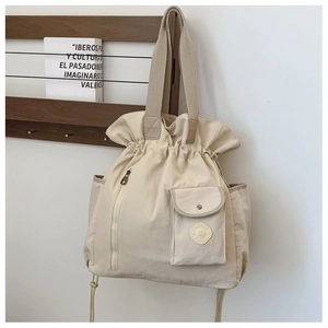 Detail of beige nylon drawstring tote bag with side pockets and smooth pleated texture