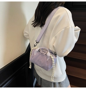 Detail view of purple drawstring bucket bag with striped rope on model in modern interior