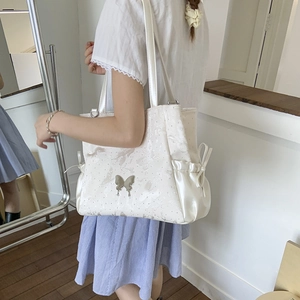 Detail of white tote bag with floral print, metal butterfly buckle and side ribbon bows
