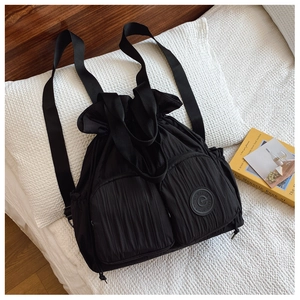 Detail view of black drawstring backpack with wrinkled nylon texture and side pockets