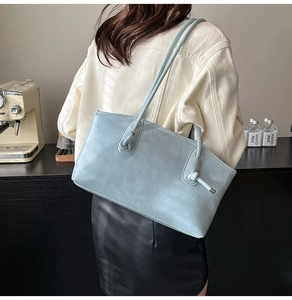 Gros plan sur un sac cabas bleu clair avec détail de nœud sur la bandoulière