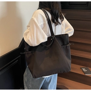 Detail of black nylon tote bag with drawstring side and comfortable shoulder straps
