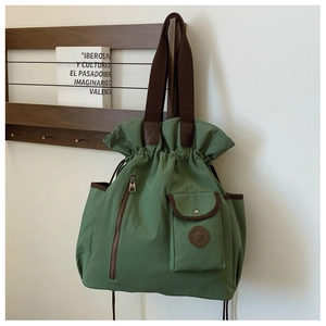 Detail of dark green canvas bucket bag with brown straps and functional zip pocket