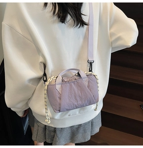 Detail of purple nylon drawstring bucket bag with branded logo and woven cord accents