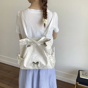 Detail of cream shoulder bag featuring butterfly floral embossing and silver metallic buckle