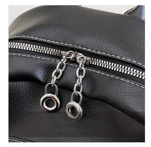 Dettaglio dello zaino in pelle nera con trama litchi, cuciture bianche e cerniere metalliche