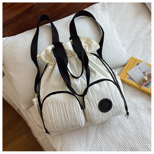 Detail of white pleated drawstring backpack with black straps and logo patch