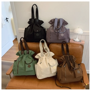 Detail of multi-color nylon drawstring tote bags displayed on a vintage leather sofa