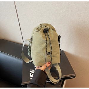 Détail du sac bandoulière en nylon vert armée montrant le cordon et le logo rond