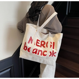 Detail of large canvas tote bag with red MERCI letter print and sturdy shoulder strap